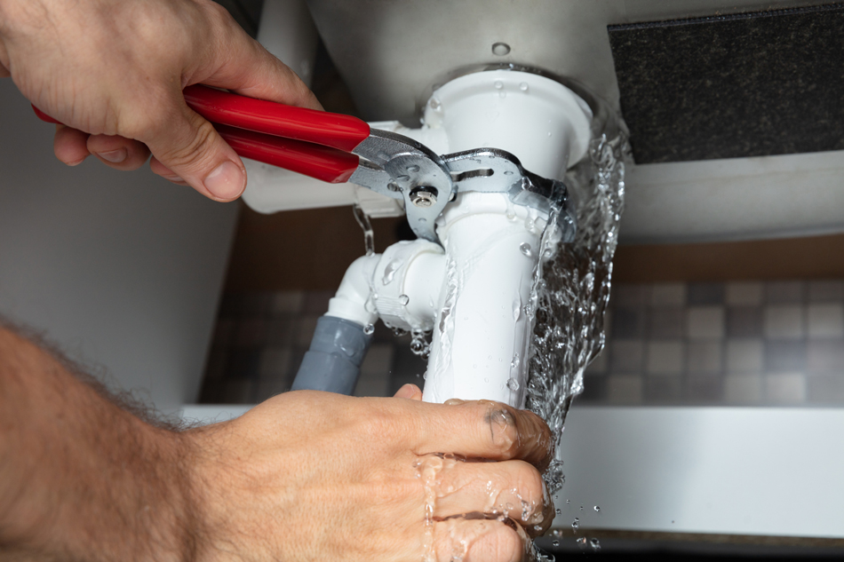 Person tightening a leaking pipe